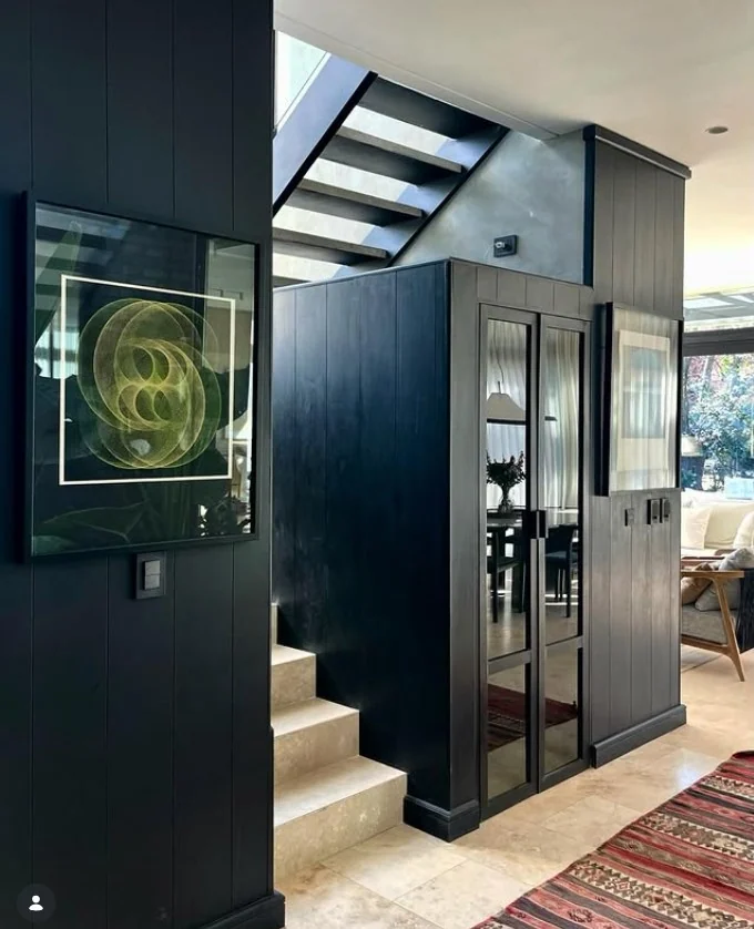 Interior de Casa Nordelta con revestimiento negro y escalera metálica